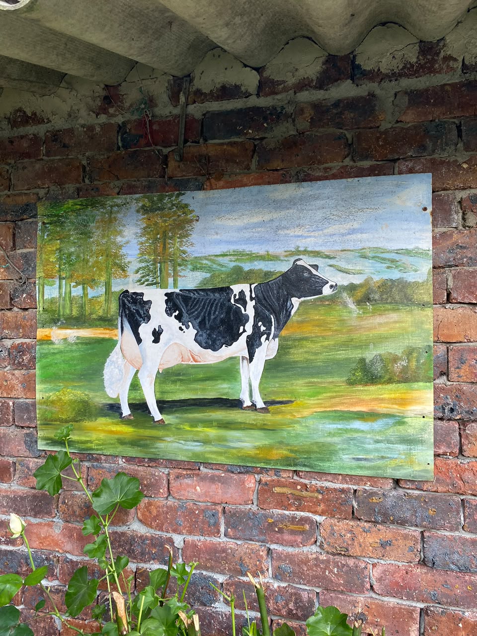 Pintura artesanal de una vaca lechera sobre muro de ladrillo